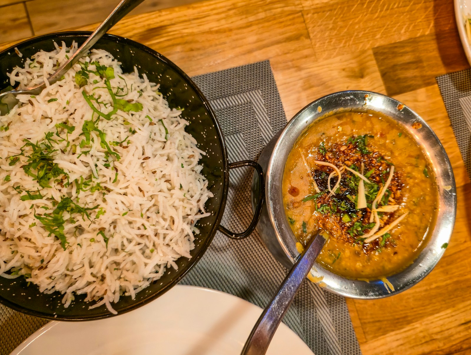 A bowl of basmati rice beside a bowl of yellow dal on a wooden table