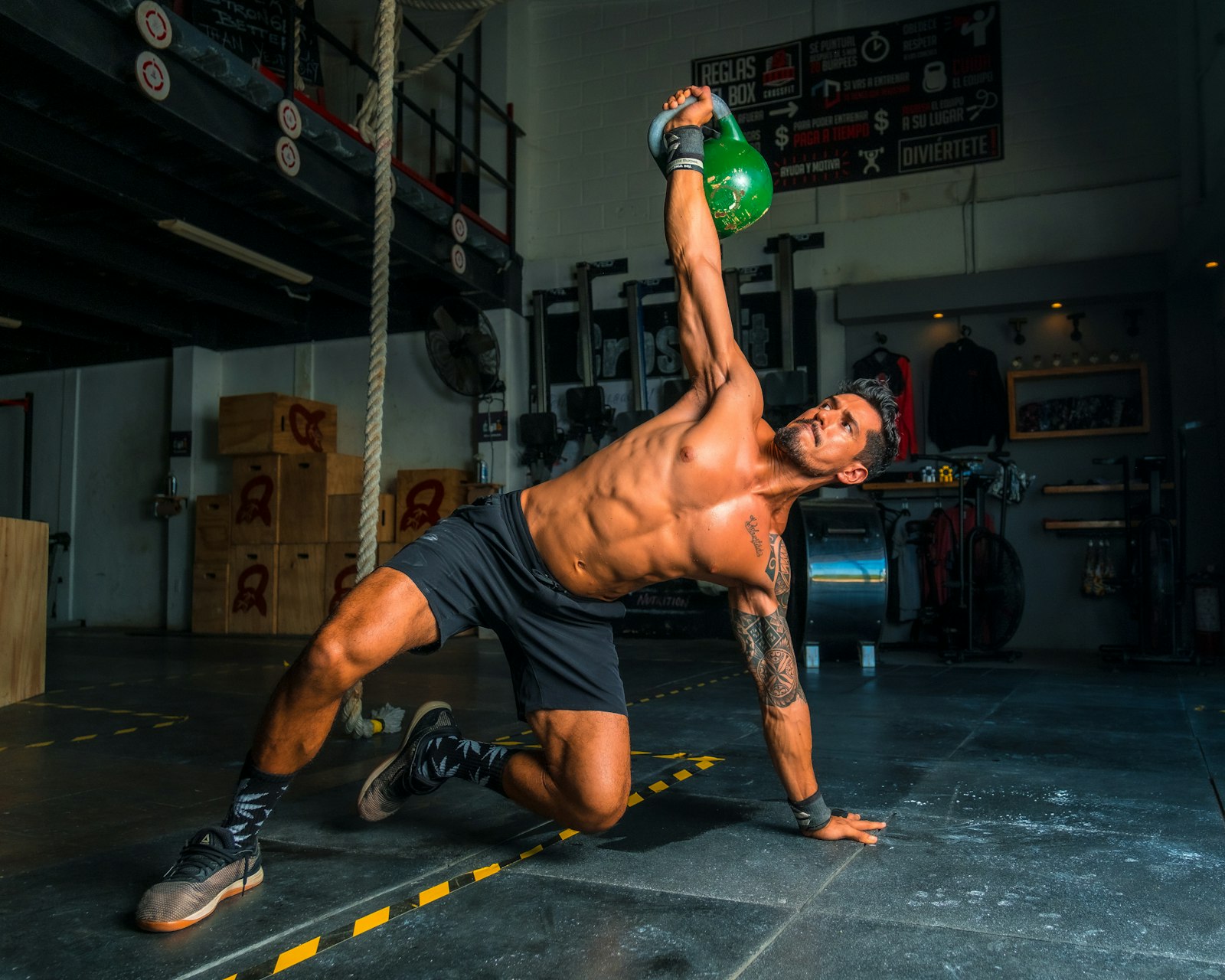 A man performing a kettlebell get-up exercise in a gym