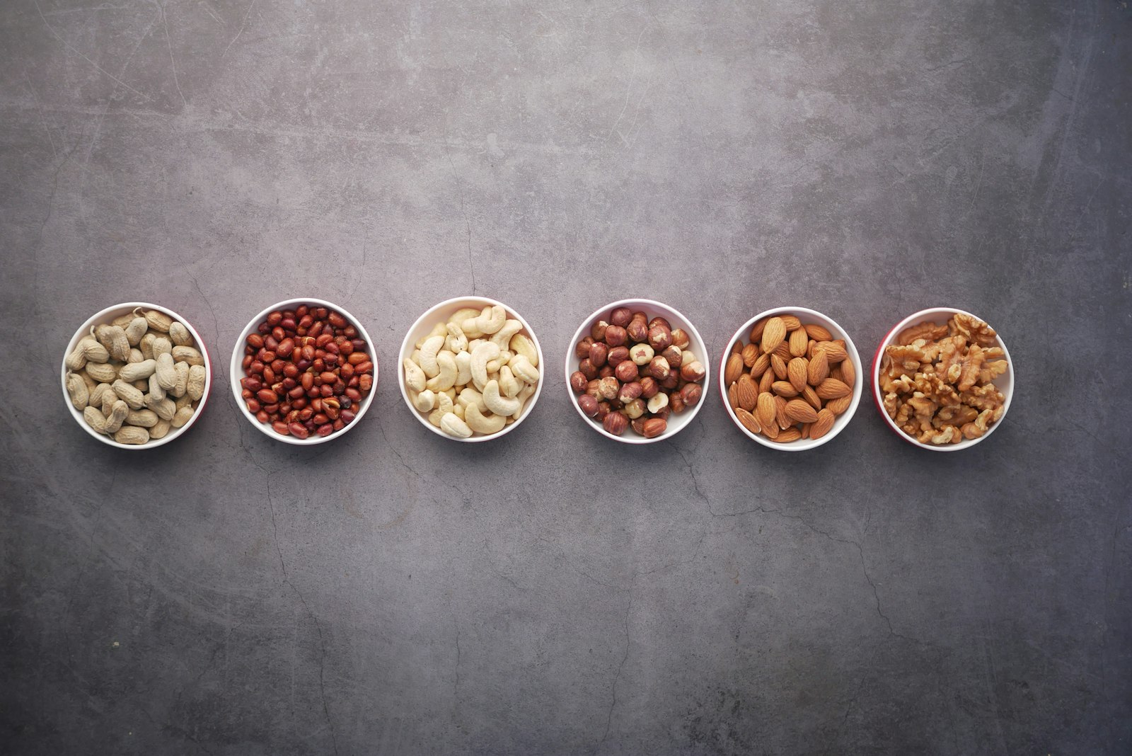 Small white bowls filled with assorted nuts and seeds
