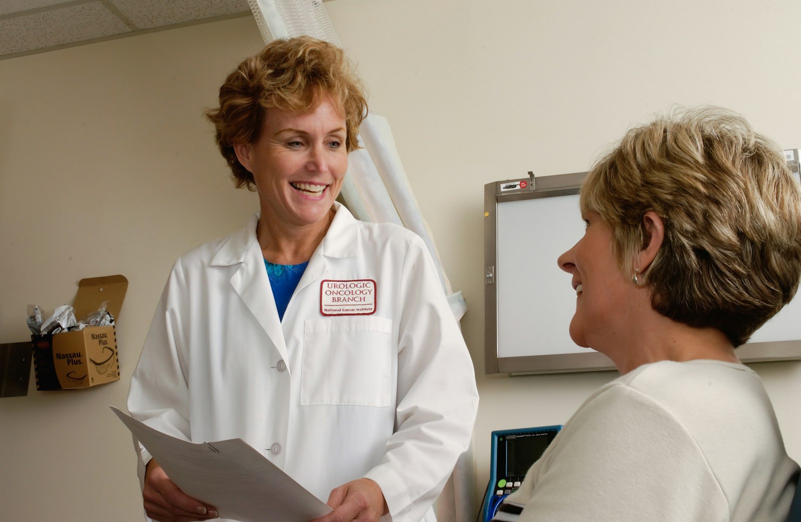 A smiling doctor in a white coat talking with a patient in a clinic