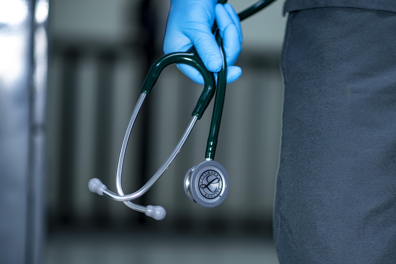 A stethoscope held by a gloved hand against a dark background