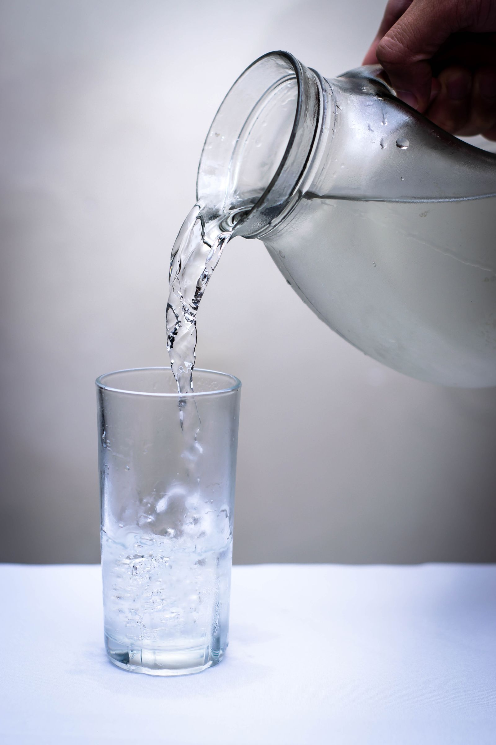 Water being poured from a jug into a clear drinking glass