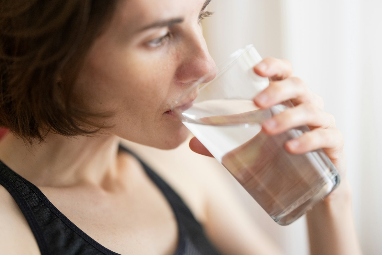 A woman drinking water from a clear glass